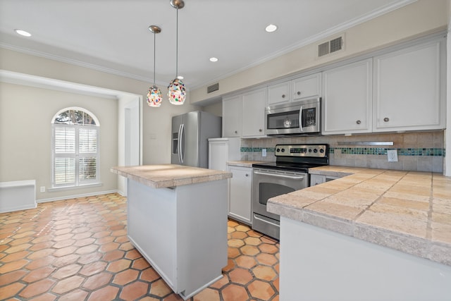 kitchen featuring decorative light fixtures, decorative backsplash, crown molding, white cabinetry, and stainless steel appliances