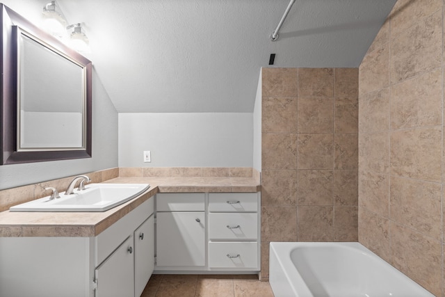 bathroom featuring a textured ceiling, tile patterned flooring, vanity, vaulted ceiling, and bathtub / shower combination