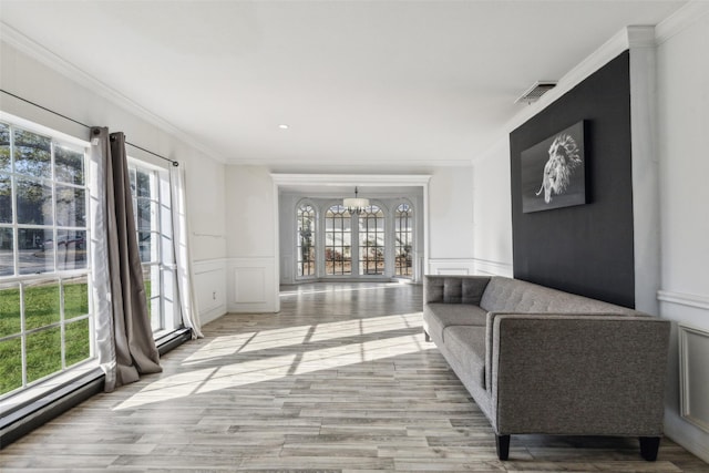 living room featuring ornamental molding, a chandelier, and light wood-type flooring