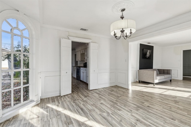 unfurnished dining area with ornamental molding, a chandelier, and light hardwood / wood-style flooring