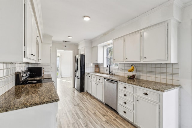 kitchen featuring white cabinets, appliances with stainless steel finishes, sink, and dark stone counters