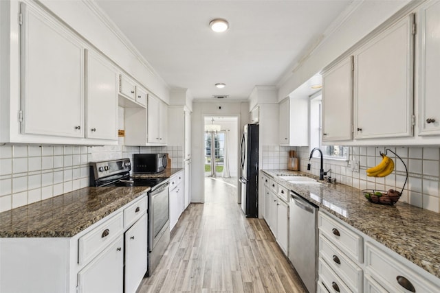 kitchen featuring white cabinets, black appliances, dark stone counters, light hardwood / wood-style floors, and sink