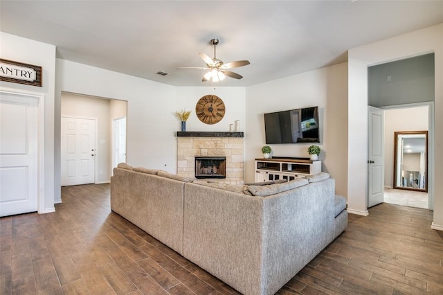 living room featuring ceiling fan, dark hardwood / wood-style flooring, and a fireplace