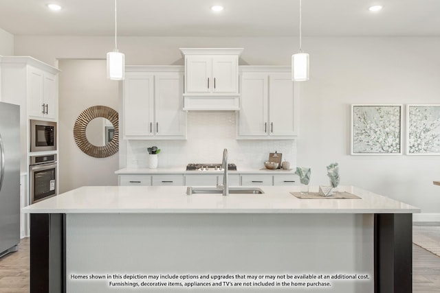 kitchen featuring white cabinets, a center island with sink, and hanging light fixtures