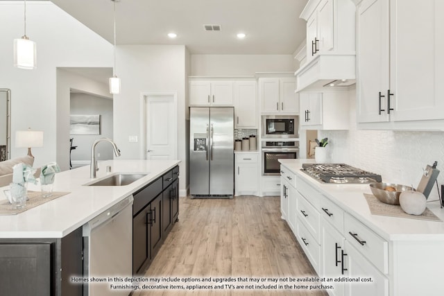 kitchen with decorative light fixtures, sink, stainless steel appliances, and white cabinetry