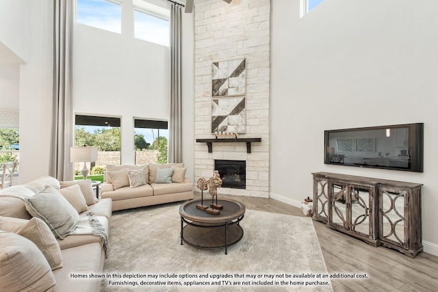 living room featuring light wood-type flooring, a fireplace, and a towering ceiling