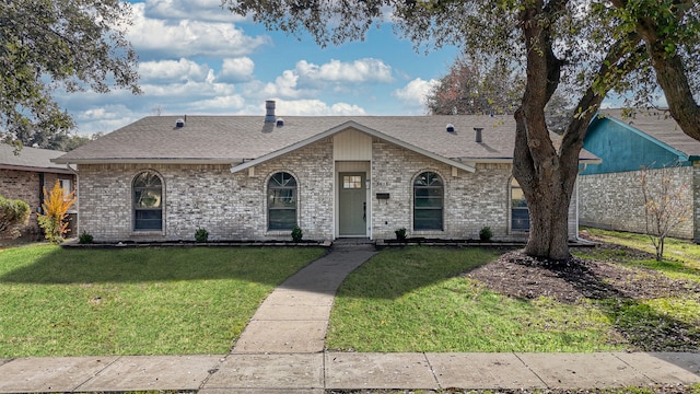 view of front of home with a front lawn, brick siding, and roof with shingles