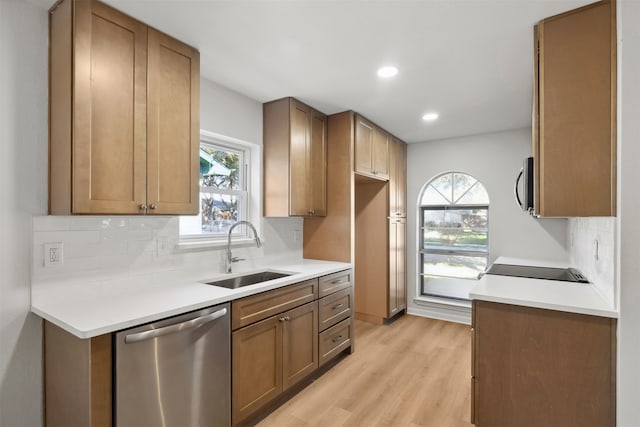 kitchen with stainless steel appliances, plenty of natural light, backsplash, light hardwood / wood-style flooring, and sink