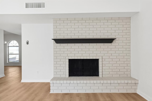 interior details with visible vents, baseboards, wood finished floors, and a fireplace