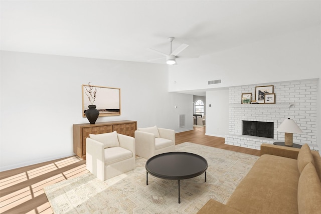 living room with visible vents, wood finished floors, a fireplace, and vaulted ceiling