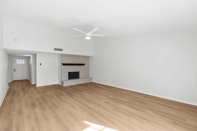 unfurnished living room with a ceiling fan, baseboards, visible vents, a brick fireplace, and light wood-type flooring