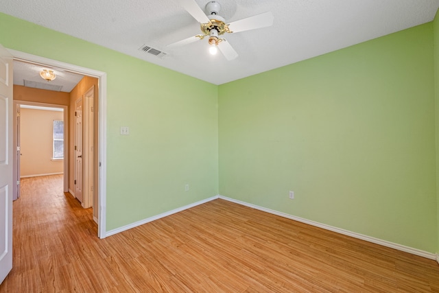 empty room featuring light wood-type flooring, ceiling fan, and a textured ceiling