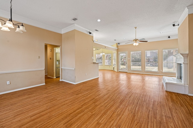 unfurnished living room with ceiling fan, a fireplace, light wood-type flooring, ornamental molding, and a textured ceiling