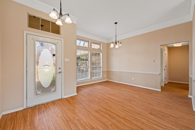 foyer with light wood-type flooring, an inviting chandelier, and crown molding