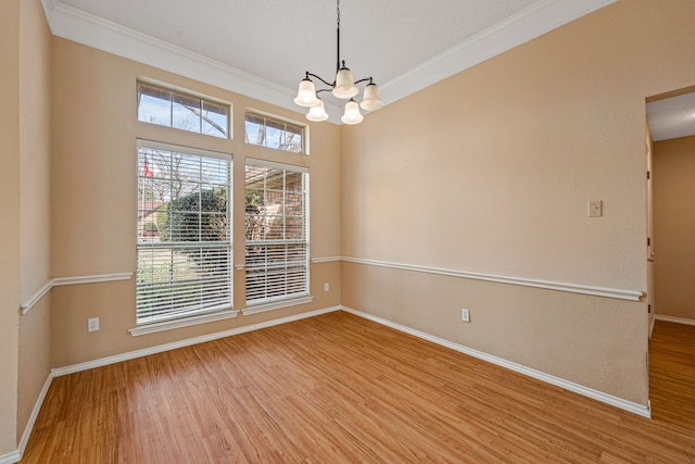 spare room with an inviting chandelier, crown molding, and light hardwood / wood-style floors