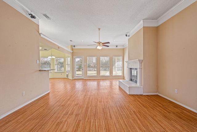 unfurnished living room featuring ceiling fan with notable chandelier, light hardwood / wood-style floors, a tile fireplace, and plenty of natural light