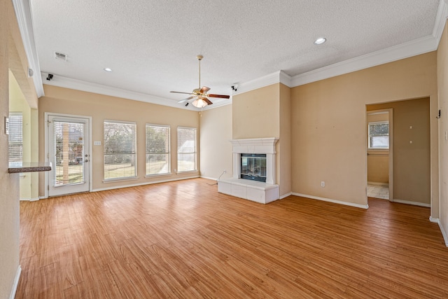 unfurnished living room with a tiled fireplace, crown molding, a textured ceiling, and light hardwood / wood-style flooring