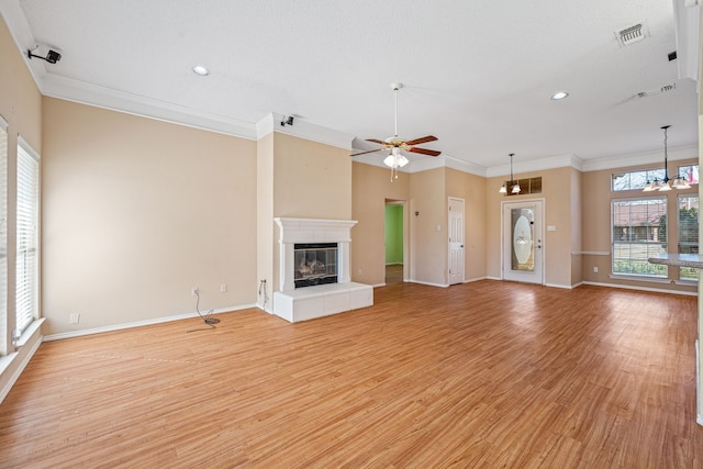 unfurnished living room with light wood-type flooring, ceiling fan with notable chandelier, ornamental molding, and a fireplace