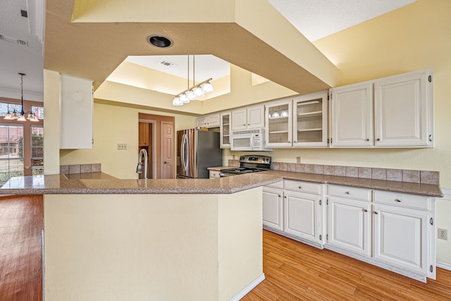 kitchen with kitchen peninsula, stainless steel appliances, white cabinets, and hanging light fixtures