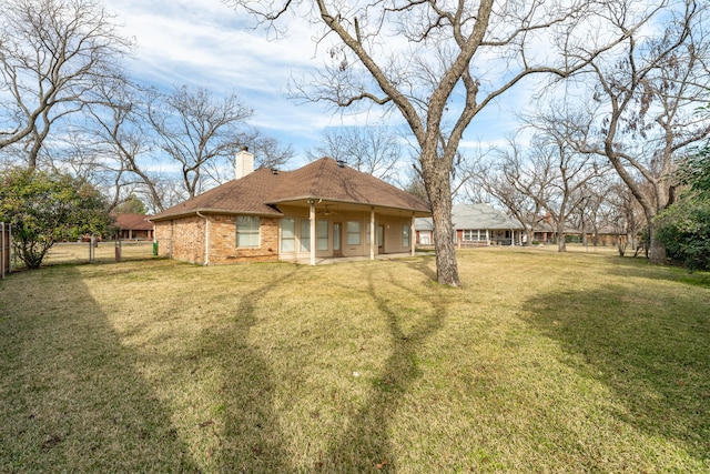 back of property featuring ceiling fan and a yard