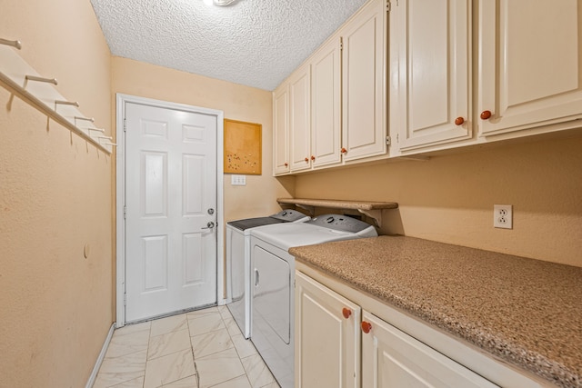 washroom with washer and clothes dryer, a textured ceiling, and cabinets