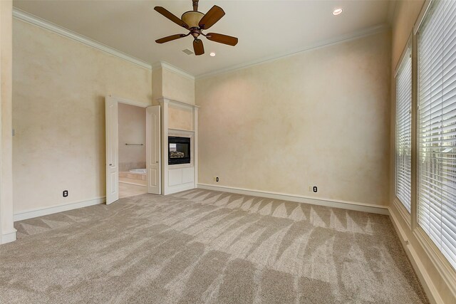 unfurnished living room with ceiling fan, ornamental molding, a fireplace, and light carpet