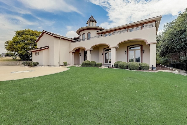 mediterranean / spanish house featuring a balcony, a front yard, and french doors