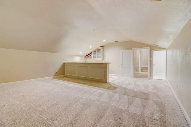 bonus room with lofted ceiling and light colored carpet