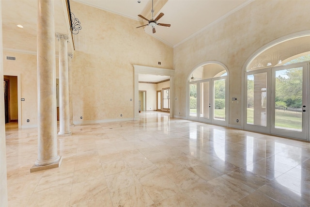 empty room featuring ornate columns, ornamental molding, a high ceiling, and ceiling fan