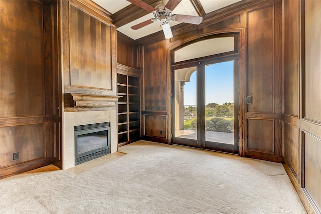 unfurnished living room featuring coffered ceiling, ornamental molding, light carpet, built in shelves, and wood walls