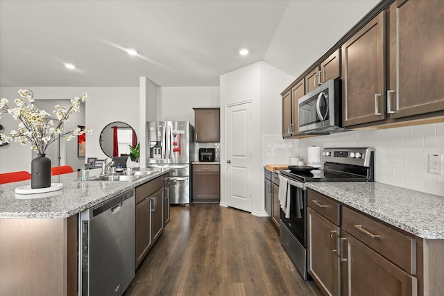 kitchen featuring dark brown cabinets, a kitchen island with sink, appliances with stainless steel finishes, dark hardwood / wood-style flooring, and light stone counters