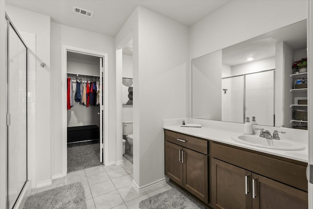 bathroom with a shower with door, tile patterned floors, vanity, and toilet