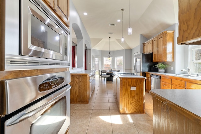 kitchen with vaulted ceiling, a kitchen island, sink, hanging light fixtures, and stainless steel appliances