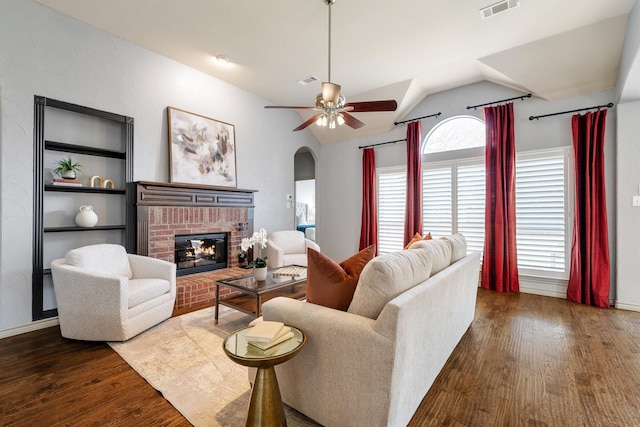 living room with a brick fireplace, dark hardwood / wood-style flooring, lofted ceiling, and ceiling fan