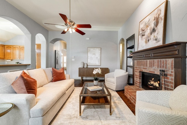 living room featuring ceiling fan, a fireplace, and light hardwood / wood-style flooring