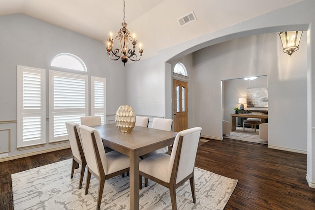 dining room with dark hardwood / wood-style flooring, an inviting chandelier, and vaulted ceiling