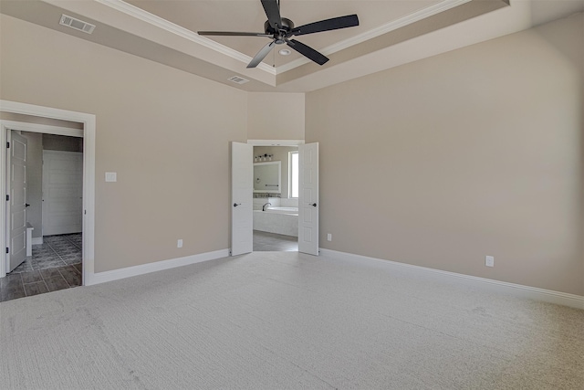 unfurnished bedroom with ceiling fan, ensuite bathroom, ornamental molding, and a raised ceiling