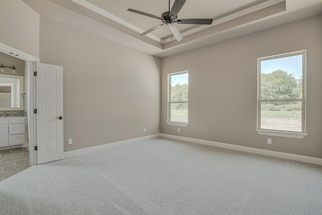 carpeted spare room featuring ceiling fan and a raised ceiling