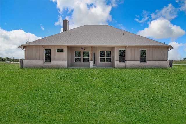 back of property featuring ceiling fan and a yard