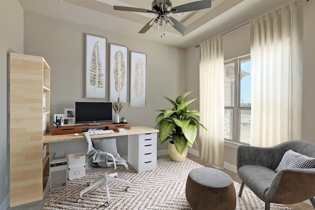 home office with ceiling fan and a tray ceiling