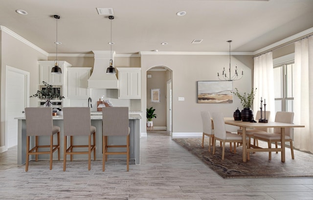 kitchen with custom exhaust hood, a breakfast bar, hanging light fixtures, and white cabinetry