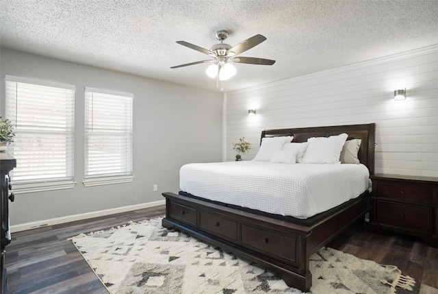 bedroom with ceiling fan, multiple windows, dark hardwood / wood-style flooring, and wood walls