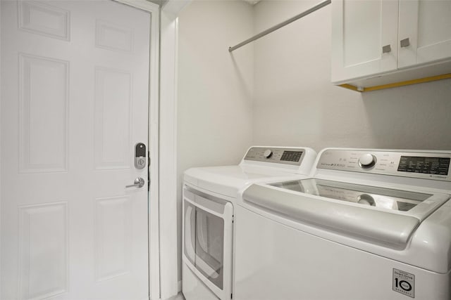 washroom with cabinets and washing machine and dryer