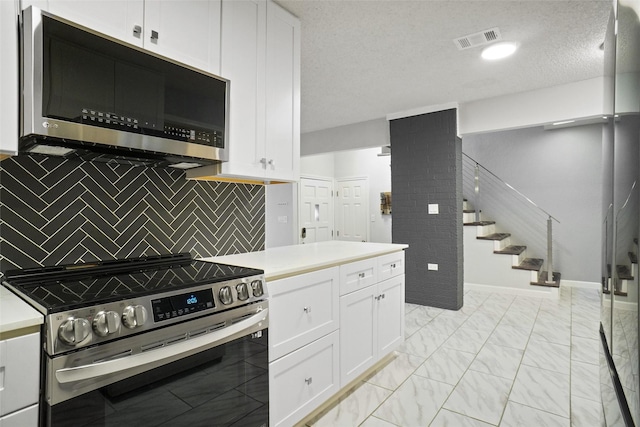 kitchen featuring backsplash, white cabinetry, stainless steel appliances, and a textured ceiling