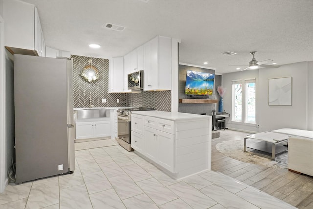 kitchen with ceiling fan, tasteful backsplash, sink, stainless steel appliances, and white cabinets