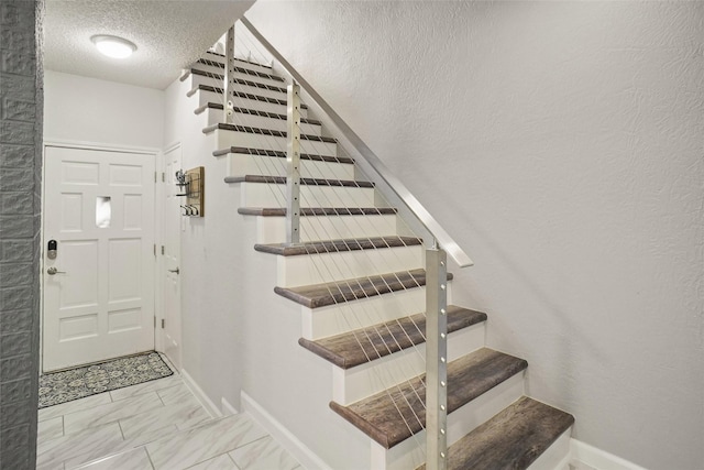 staircase featuring a textured ceiling