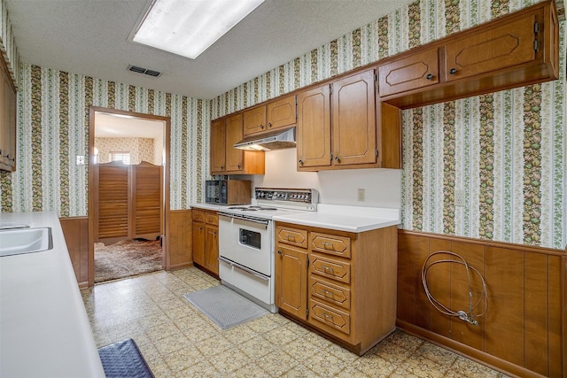 kitchen with a textured ceiling, wooden walls, and white range with electric cooktop