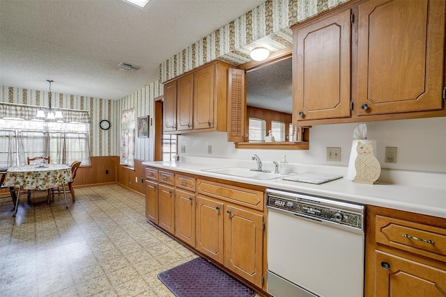 kitchen featuring a notable chandelier, sink, white dishwasher, hanging light fixtures, and a textured ceiling