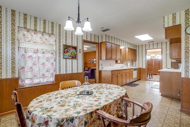 dining area with a textured ceiling, sink, wooden walls, and a notable chandelier