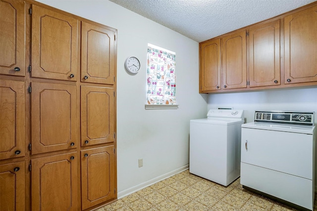 clothes washing area with separate washer and dryer, a textured ceiling, and cabinets